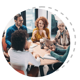 Employees sitting at a table talking in an office setting during the day 